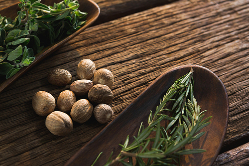 Close-up of nutmegs and rosemary herbs  on a wooden table