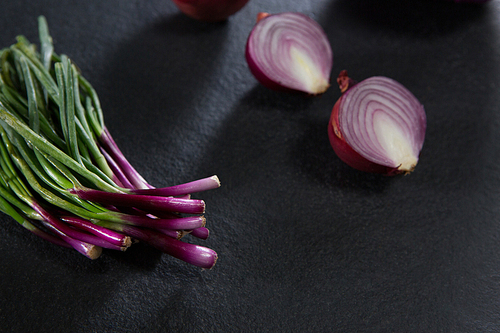 Close-up of scallions and halved of onion on black background