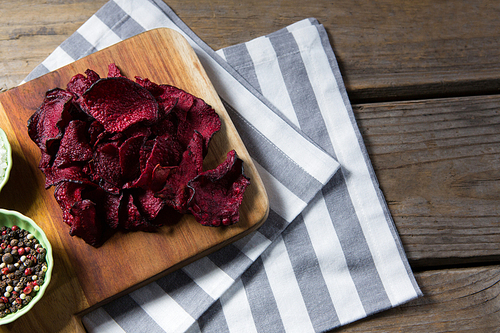 Close-up of dried beetroot with bowl of black pepper on chopping board