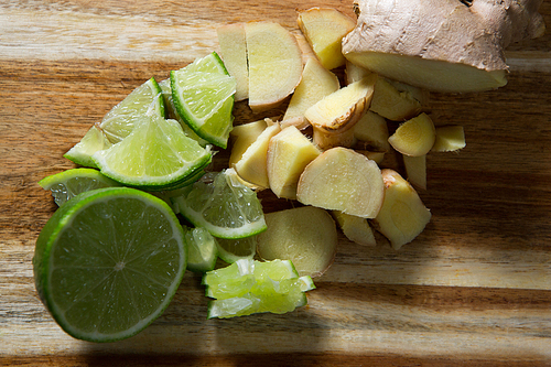 Close-up of chopped ginger and halved lemon on wooden board