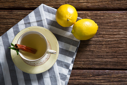 Cup of tea with lemon and cinnamon stick on wooden table