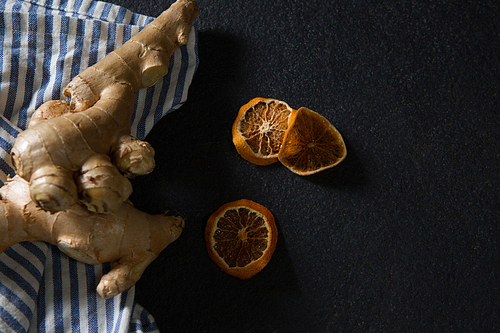 Overhead of ginger and dried orange sliced on black background