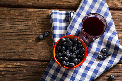 Overhead of bowl of blueberries and juice on wooden table