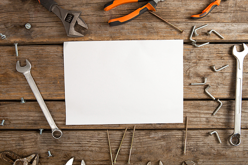 Overhead view of blank paper amidst hand tools on wooden table