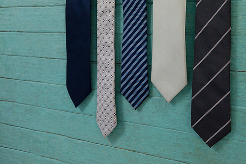 Close up of various neckties hanging by green wooden wall