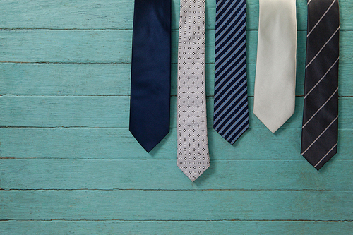 Various neckties hanging by green wooden wall