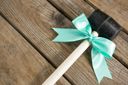 Close up of hammer with ribbon bow on wooden table