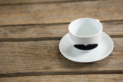 Close up of mustache on cup at wooden table