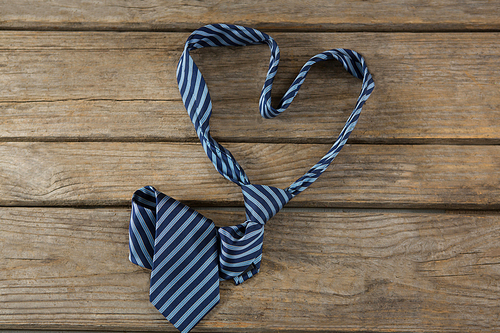 Overhead view of neckties in heart shape on wooden table