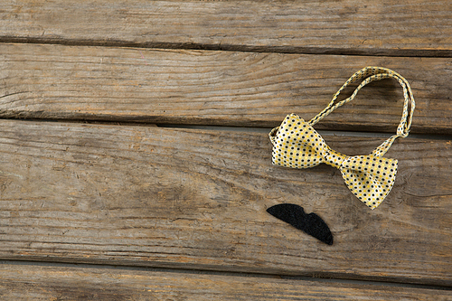 High angle view of mustache by bow tie on wooden table