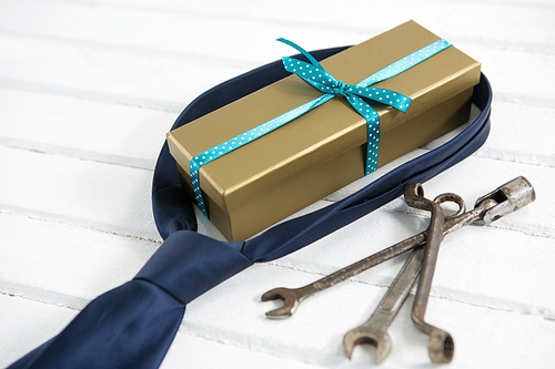 Close up of gift and necktie by work tools on wooden table