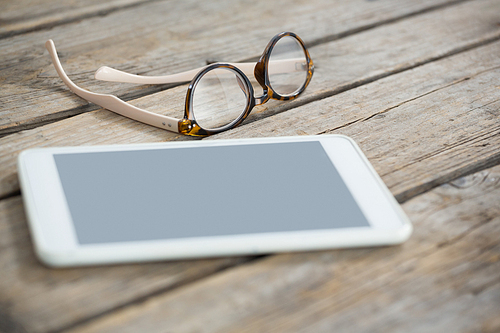 Close up of eyeglasses and tablet computer on wooden table