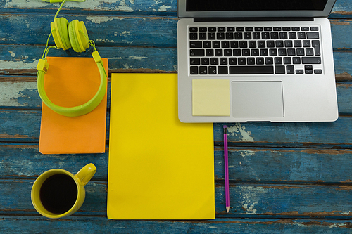 Overhead of black coffee and office accessories on wooden plank