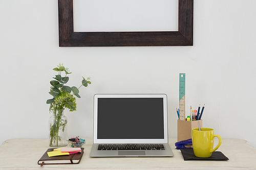 Laptop and various office accessories on table in office