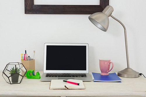 Laptop and various office accessories on table in office