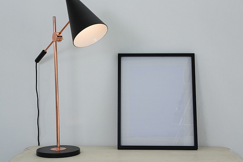 Picture frame and illuminated lamp on wooden table