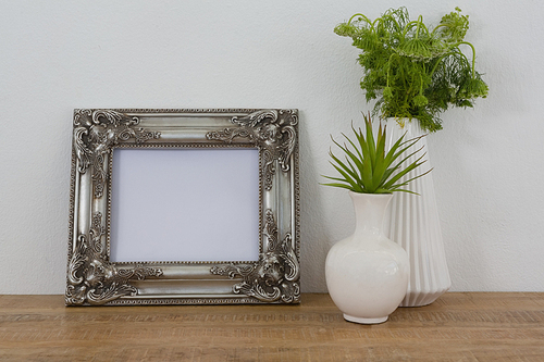 Picture frame and vase arranged on table