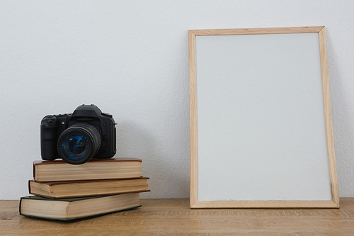 Picture frame, books and digital camera arranged on table