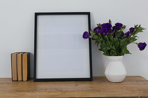 Picture frame and flower vase arranged on table