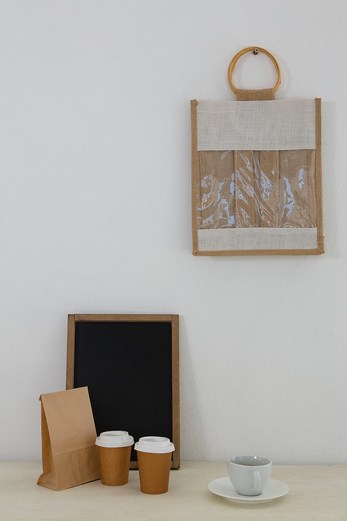 Coffee, parcel, slate and bag against white wall