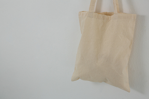 Close-up of beige bag hanging against white wall