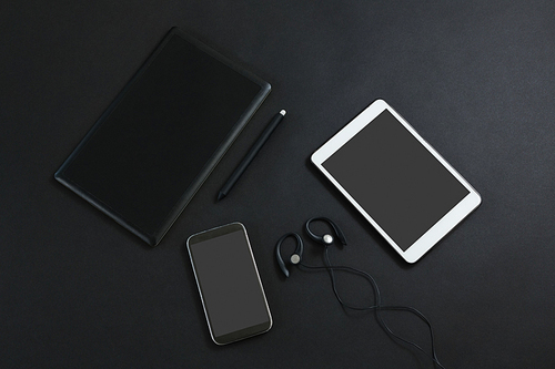 Overhead of mobile phone, graphic tablet, headphones, pen and digital tablet on black background