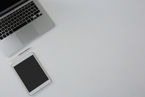 Overhead of laptop, digital tablet and pen on white background