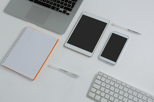 Overhead of various electronic gadgets and book on white background