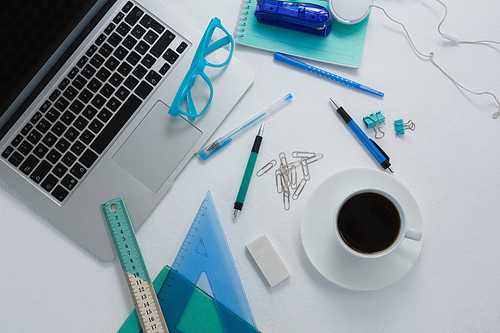 Overhead of laptop, black coffee and stationery on white background