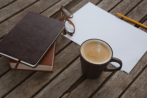 Overhead of organizer, coffee, spectacles, pencil and paper on wooden plank