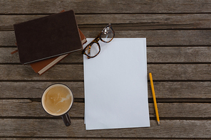 Overhead of organizer, coffee, spectacles, pencil and paper on wooden plank