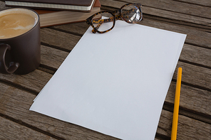 Close-up of organizer, coffee, spectacles, pencil and paper on wooden plank