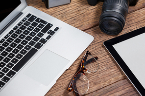 Close-up of digital camera, digital tablet, laptop, spectacle on table in studio