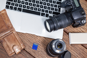 Close-up of digital camera, lens, memory card, laptop on table in studio