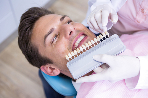 High angle view of dentist holding equipment while examining patient at medical clinic