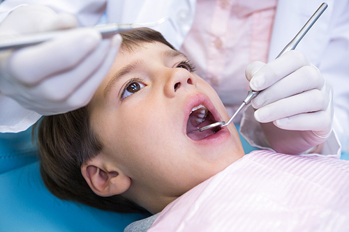 Close up of dentist holding equipment while examining boy at medical clinic