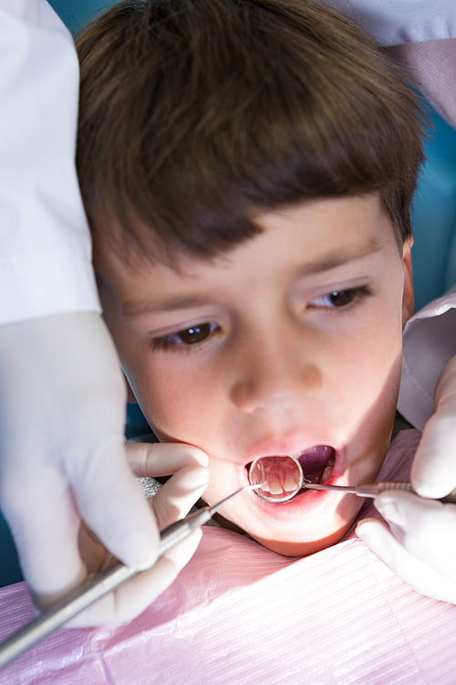 Close-up of boy looking away while receiving dental treatment at clinic