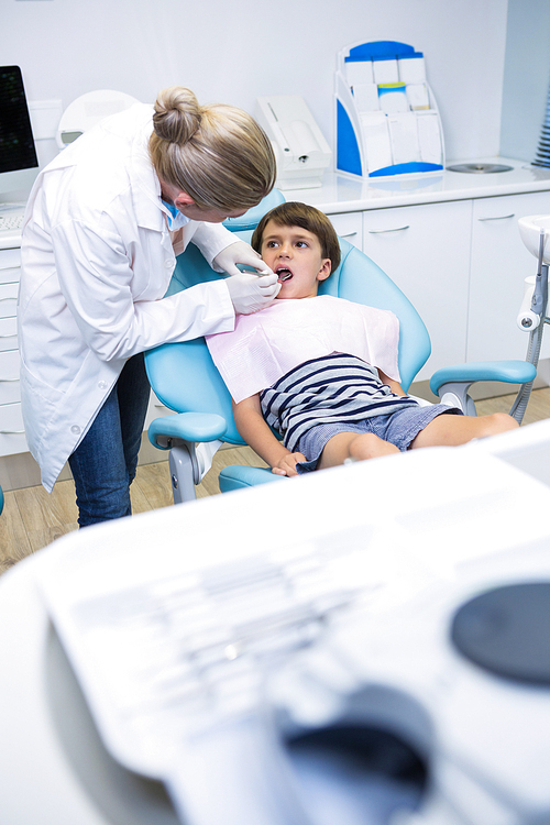 Dentist giving dental treatment to boy at clinic