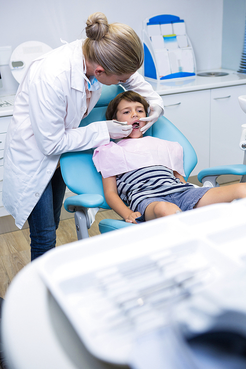 Female doctor examining boy at dental clinic