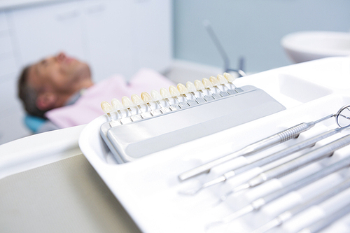 Close-up of medical equipment  on table against man lying on dentist chair
