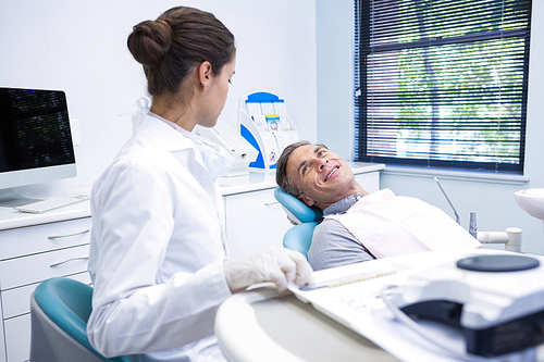Smiling patient discussing with dentist at medical clinic