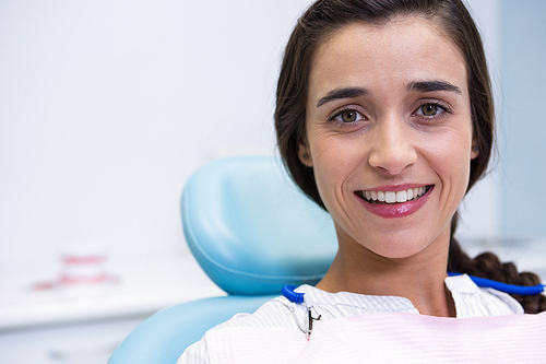Portrait of patient smiling while sitting on chair at dental clinic
