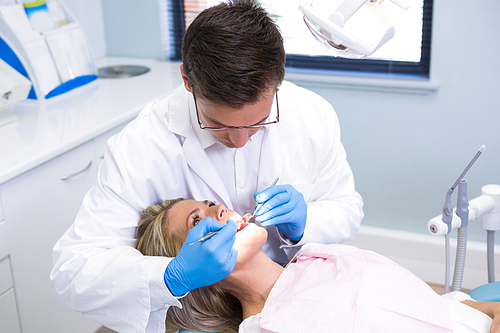 High angle view of dentist examining woman with dental equipments at medical clinic