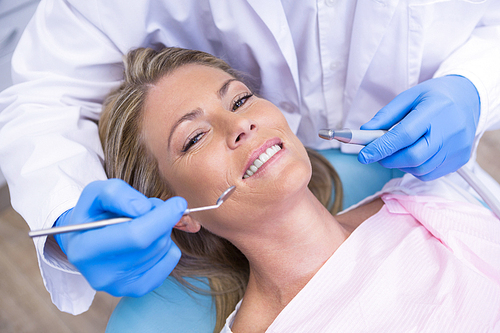 High angle portrait of woman by dentist dolding tool at medical clinic