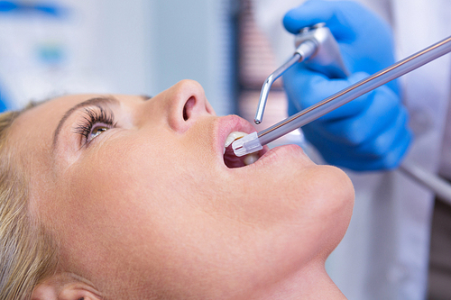 Extreme close up of dentist examining woman at dental clinic