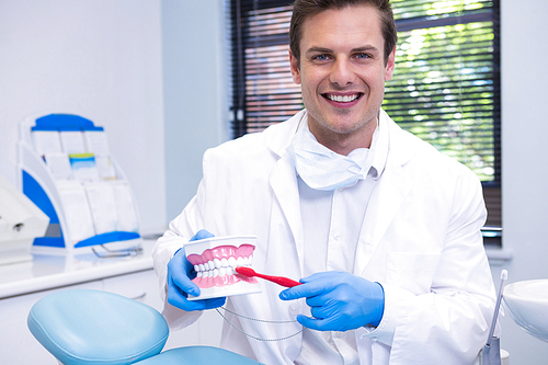Portrait of dentist brushing dental mold while sitting at clinic