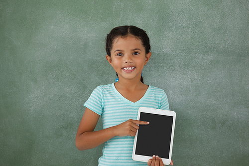 Young girl holding digital tablet against chalk board