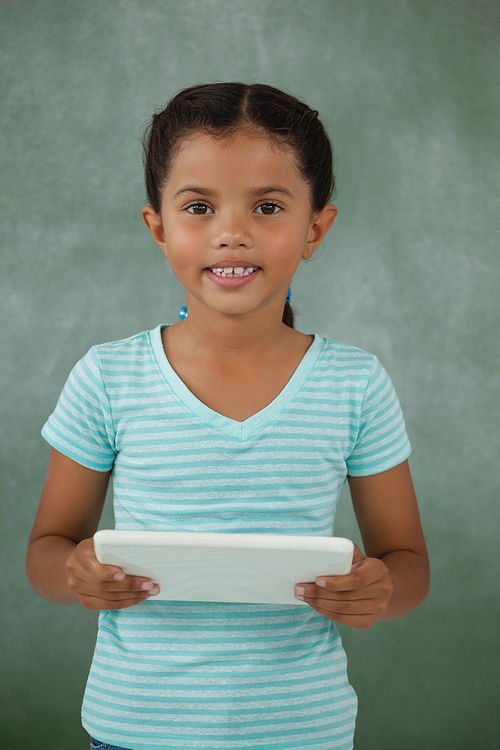 Young girl holding digital tablet against chalk board