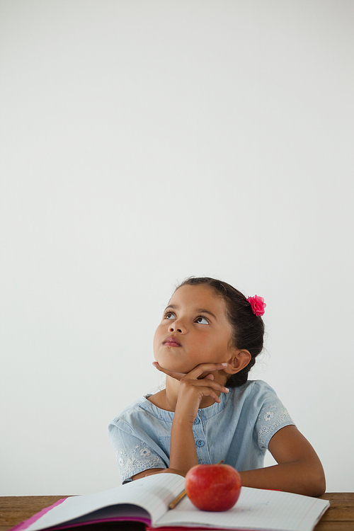 Thoughtful young girl sitting against white background