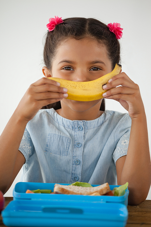 Adorable schoolgirl having breakfast against white background